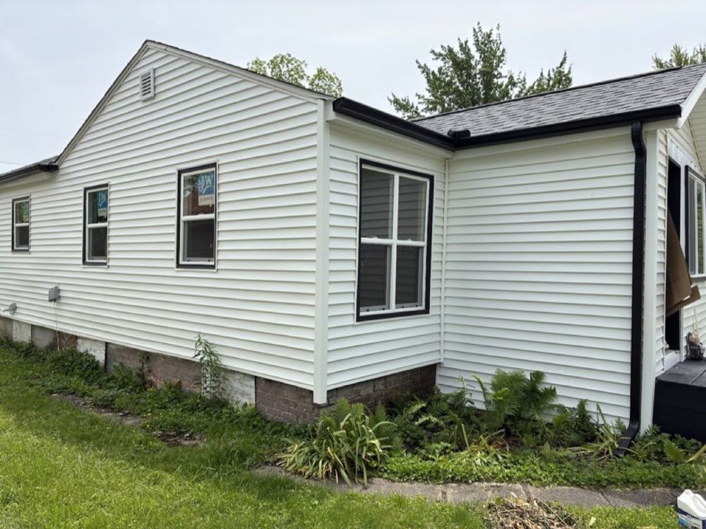 Finished white vinyl siding on a home with fresh gutters and downspout