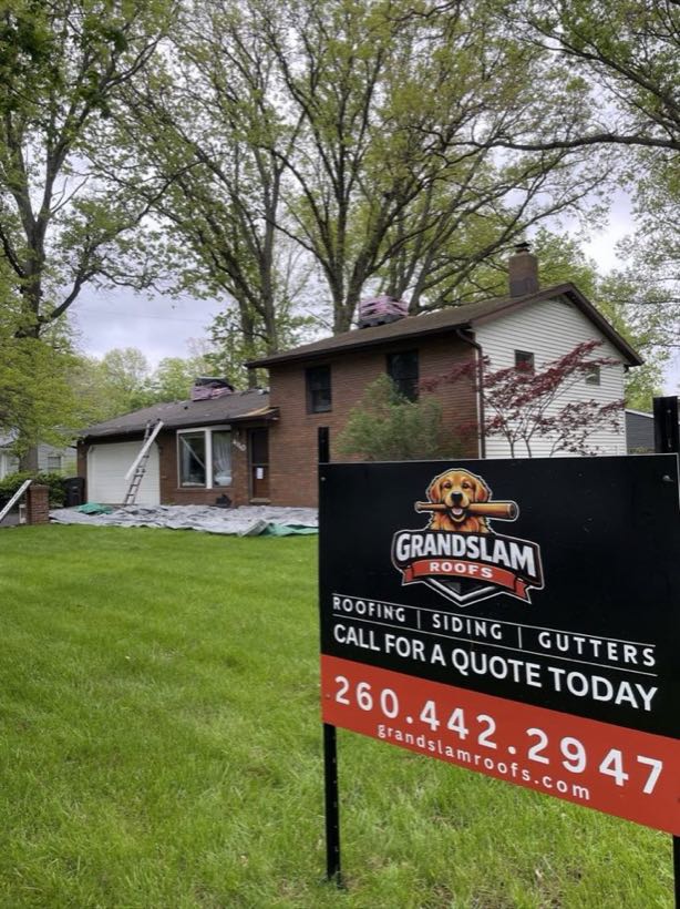 Grand Slam Roofs branded yard sign — roofing, siding, gutters — at a re-roof in progress